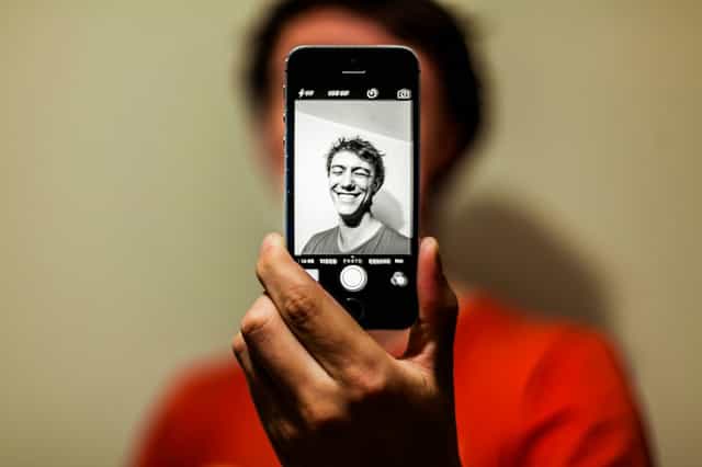 Pessoa segurando um smartphone com a câmera frontal aberta para uma selfie