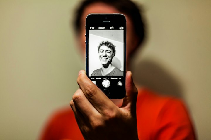 Pessoa segurando um smartphone com a câmera frontal aberta para uma selfie