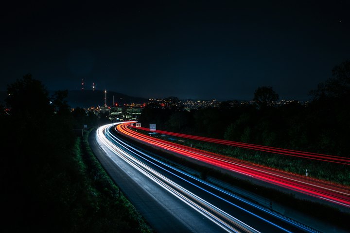 Rodovia à noite em longa exposição, com rastros de faróis