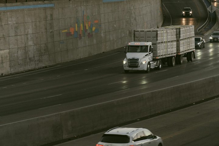 Caminhão carregando contêineres brancos em uma rodovia